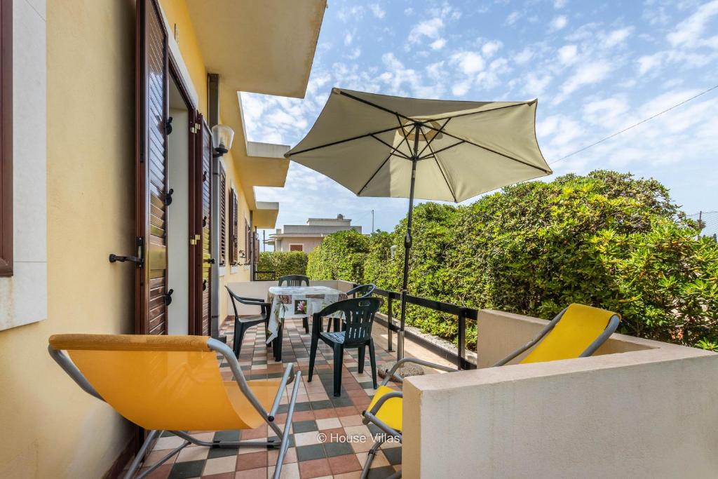 a balcony with a table and chairs and an umbrella at House&Villas - Residence Miramare in Avola