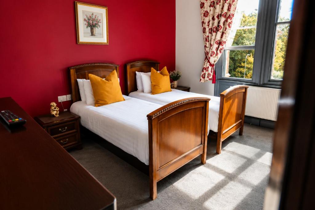 a red bedroom with two beds and a window at The Godwins in Hereford