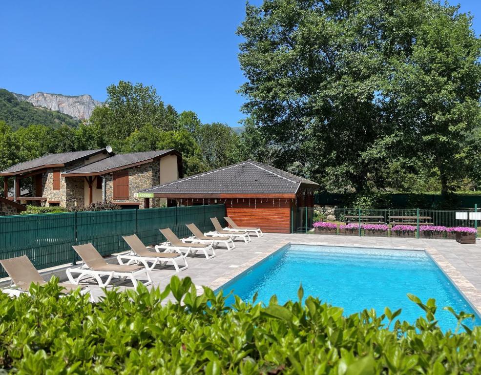 a swimming pool with lounge chairs and a house at Les Granges de Leo in Aston