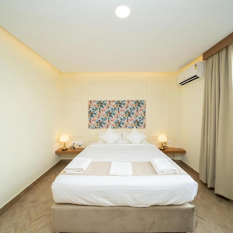 a bedroom with a large white bed with two lamps at The Clock Tower Inn in Bangalore