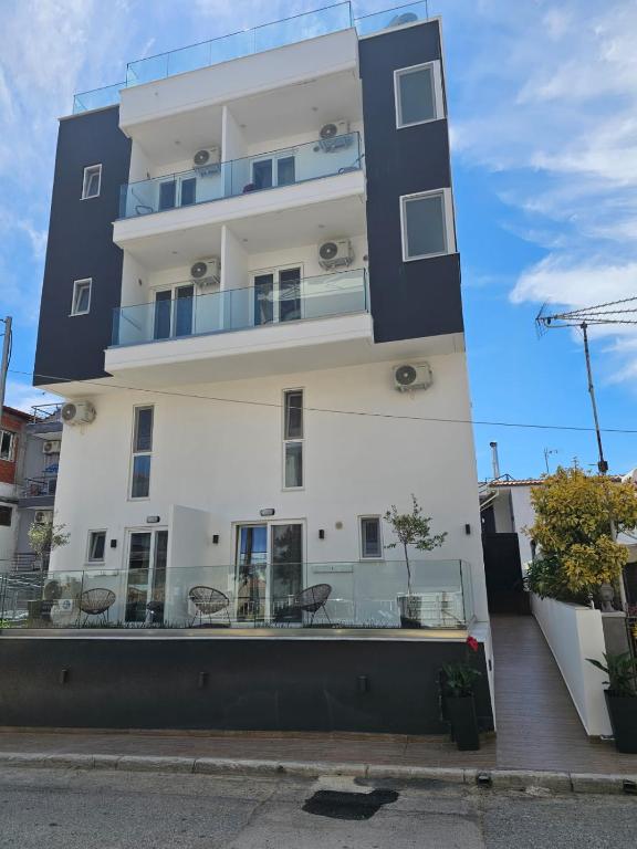 a tall white building with chairs in front of it at Diamond Suite in Nea Kallikrateia