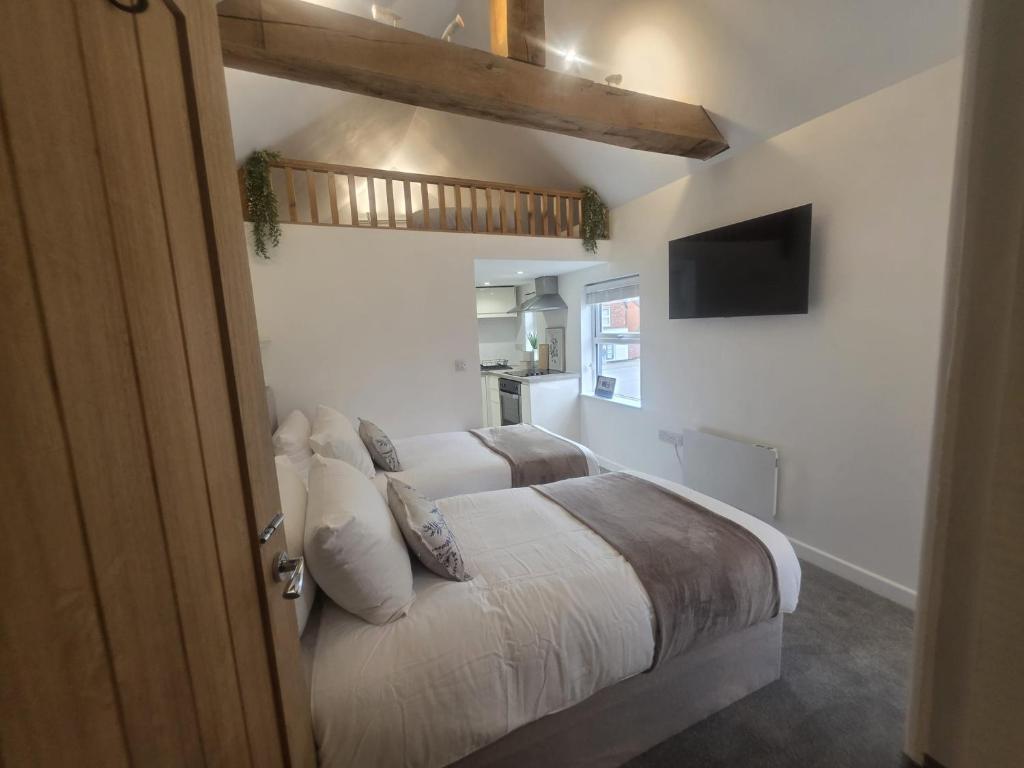 a bedroom with a bed with white sheets and a television at The Loft Studio Westbury in Westbury
