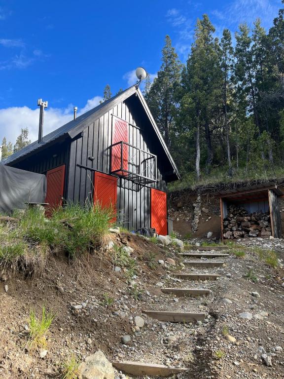 a barn with red doors and stairs in front of it at Cabaña sobre el Lago Cholila in Cholila