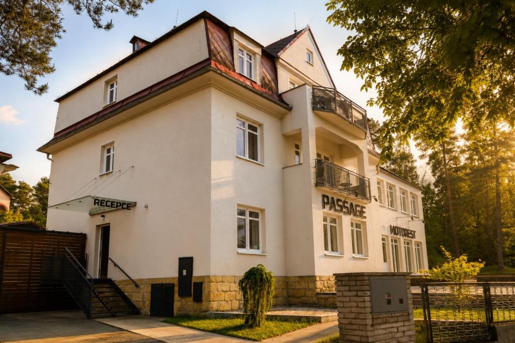 a large white building with a tree at Pokoje Pasáž in Doksy