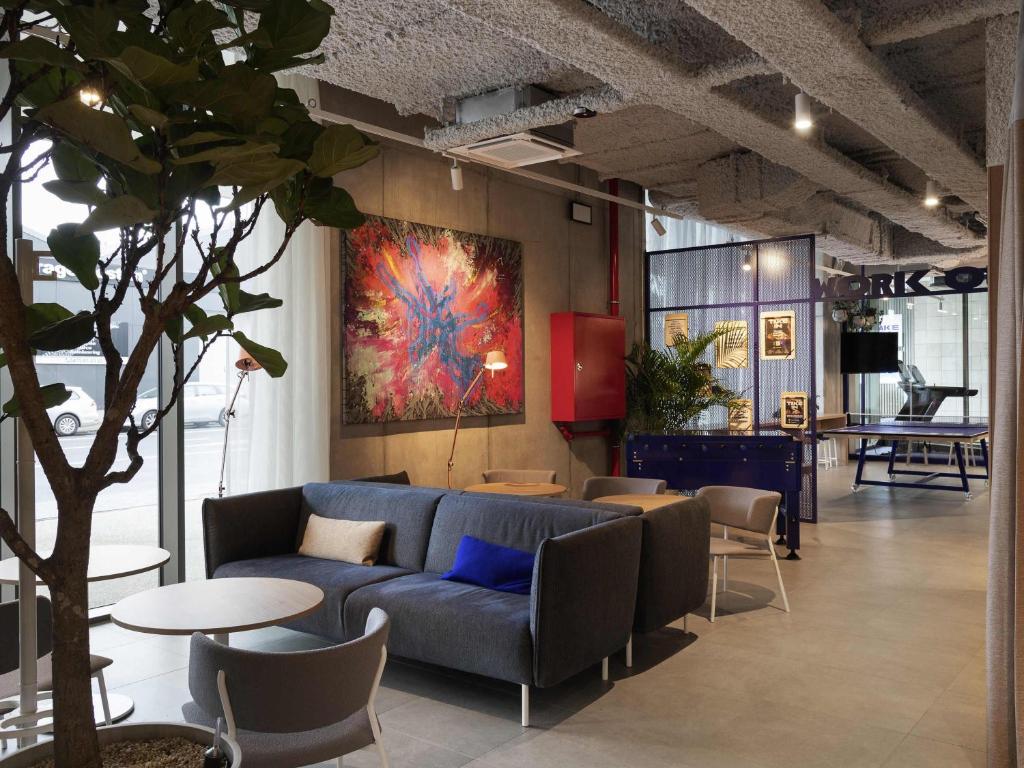 a living room with a couch and tables and a painting at Adagio Access Gent Centrum Dampoort in Ghent