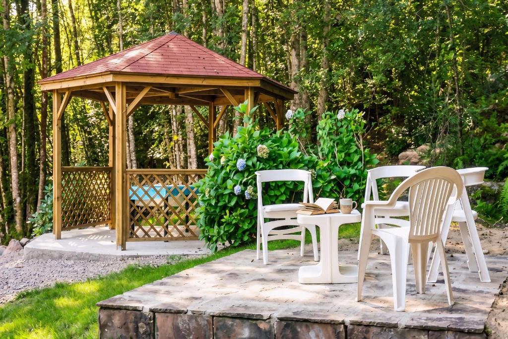 a wooden gazebo with chairs and a table at Villa Pré d'Oro 5 étoiles 10 personnes, spa privé, nature, Vosges Saônoises in Amage