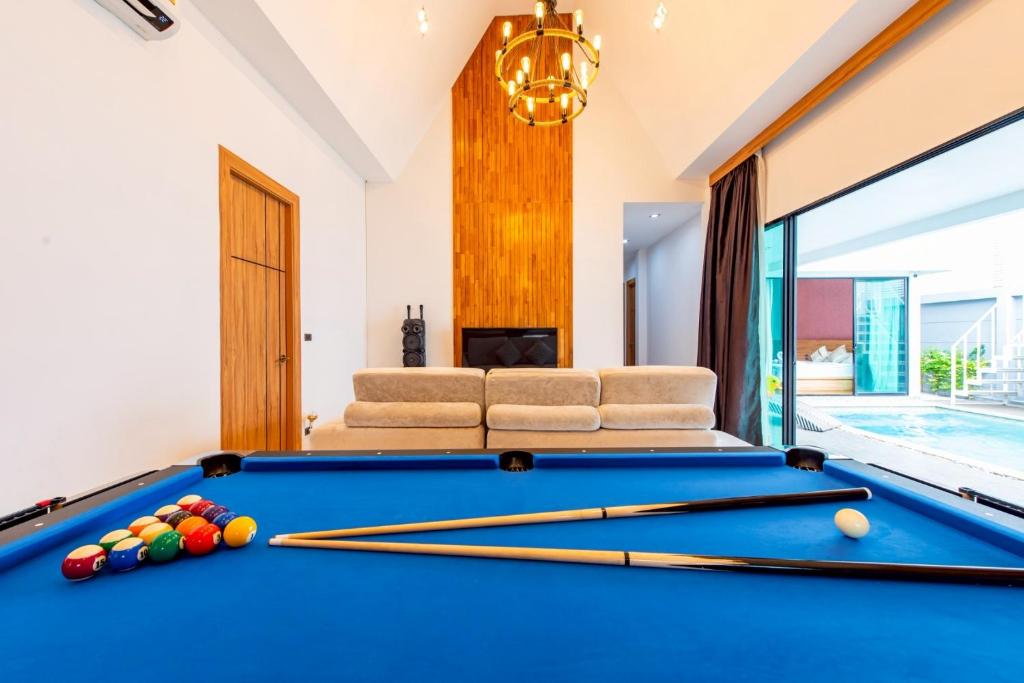 a pool table in a living room with a swimming pool at King Arthur Pool Villa in Nong Prue