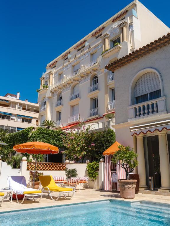 a hotel with a swimming pool in front of a building at Hôtel Juana in Juan-les-Pins
