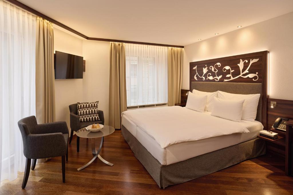 ein Hotelzimmer mit einem Bett und einem Stuhl in der Unterkunft Hotel Scheuble in Zürich