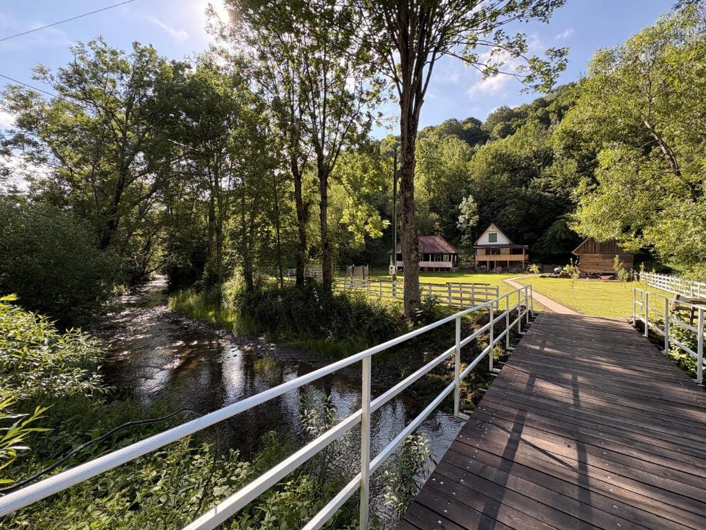 a wooden bridge over a river with a house in the background at Pompei Village in Cojocani