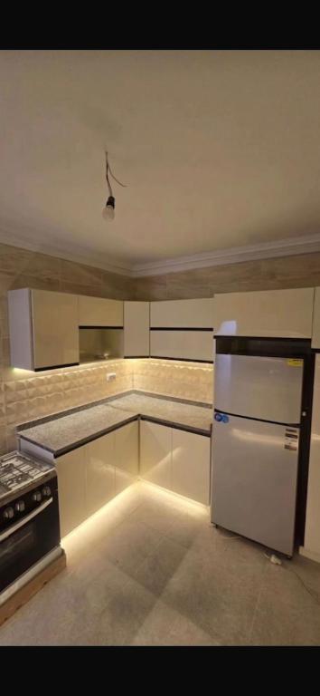 a kitchen with a white refrigerator and a stove at تاون داون in El Dab‘a