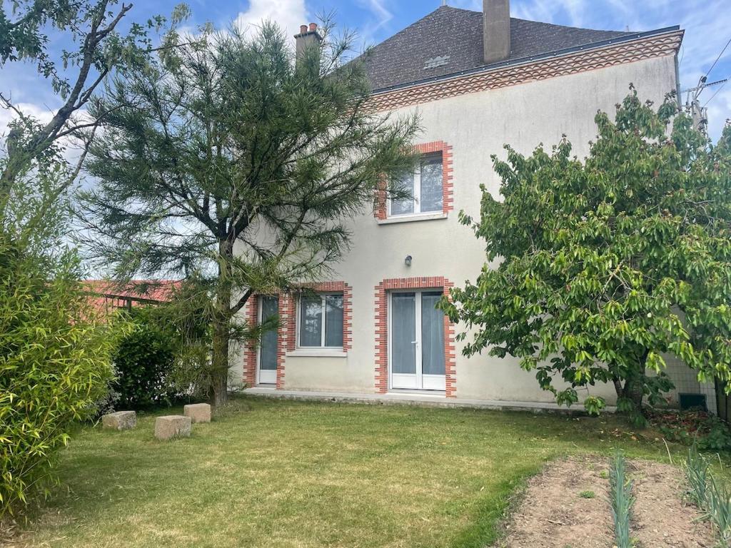 a white house with a tree in the yard at Maison de Tisserand 10 pers in Gesté