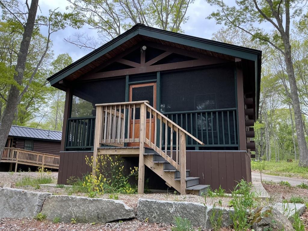 a cabin in the woods with a porch and a deck at Rivers Edge Cabins - Deer Run in Cushing
