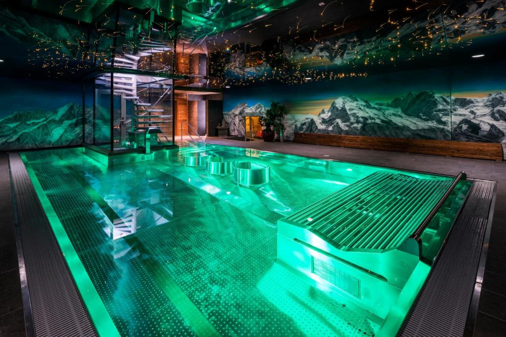 a large swimming pool in a building with a mountain mural at Silvana Mountain Hotel in Zermatt
