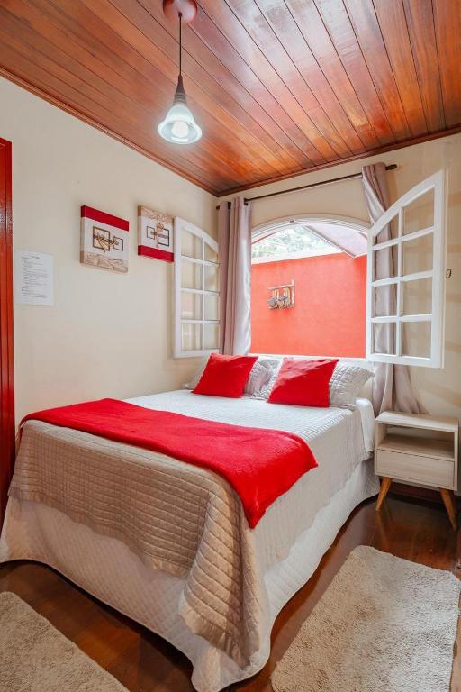 a bedroom with a large bed with red pillows at Suites CAMINHO DA FÉ in Campos do Jordão