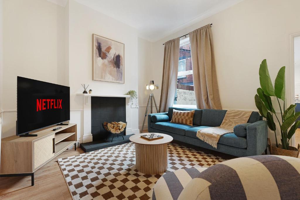 a living room with a blue couch and a tv at Charming 4BR Retreat in Hull Sleeps 8 by Stay With Us in Hull