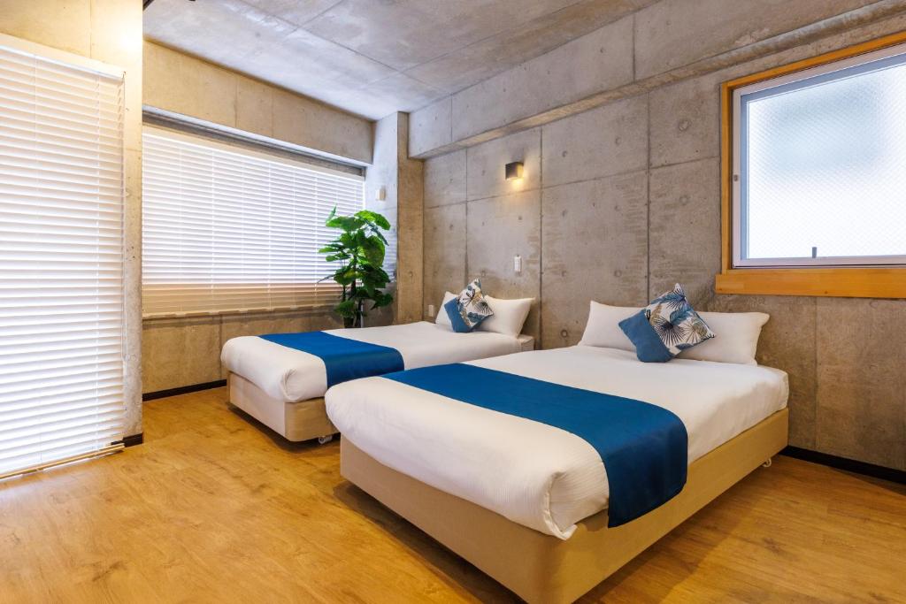 two beds in a room with two windows at Kokusai Street Garden Hotel in Naha
