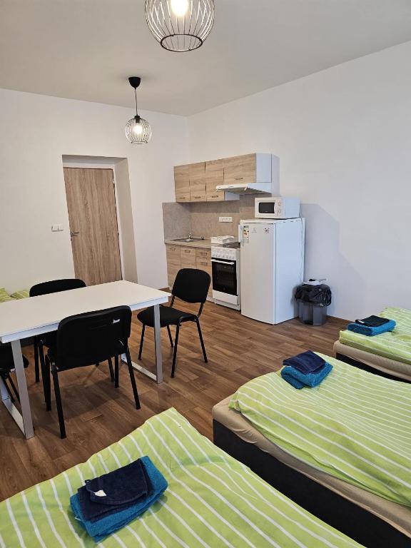 a room with two beds and a table and a kitchen at Studio Klicperova in Chlumec nad Cidlinou