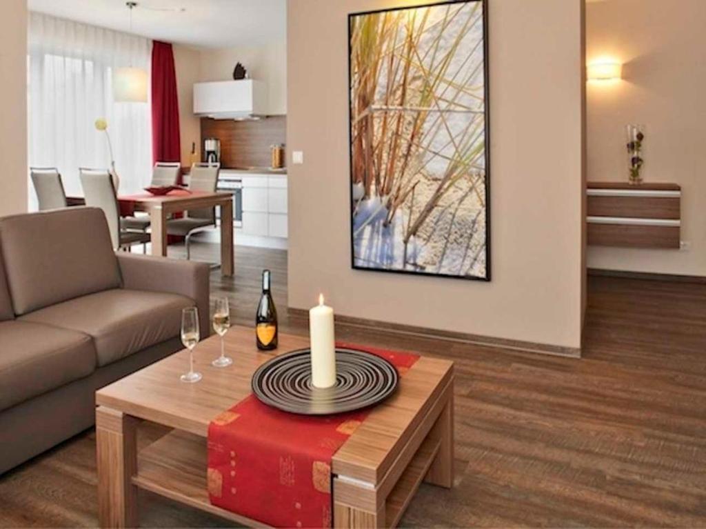 a living room with a couch and a table with a candle at Dünenhaus Aurell, App 4 mit Sauna in Heringsdorf