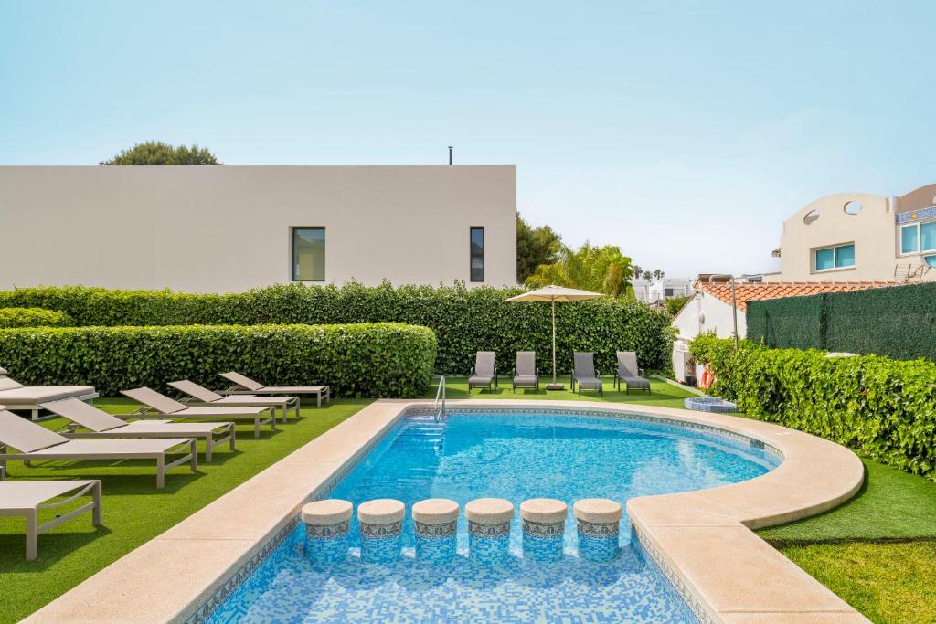 a swimming pool with chaise lounge chairs and a building at Albir Experience in Albir