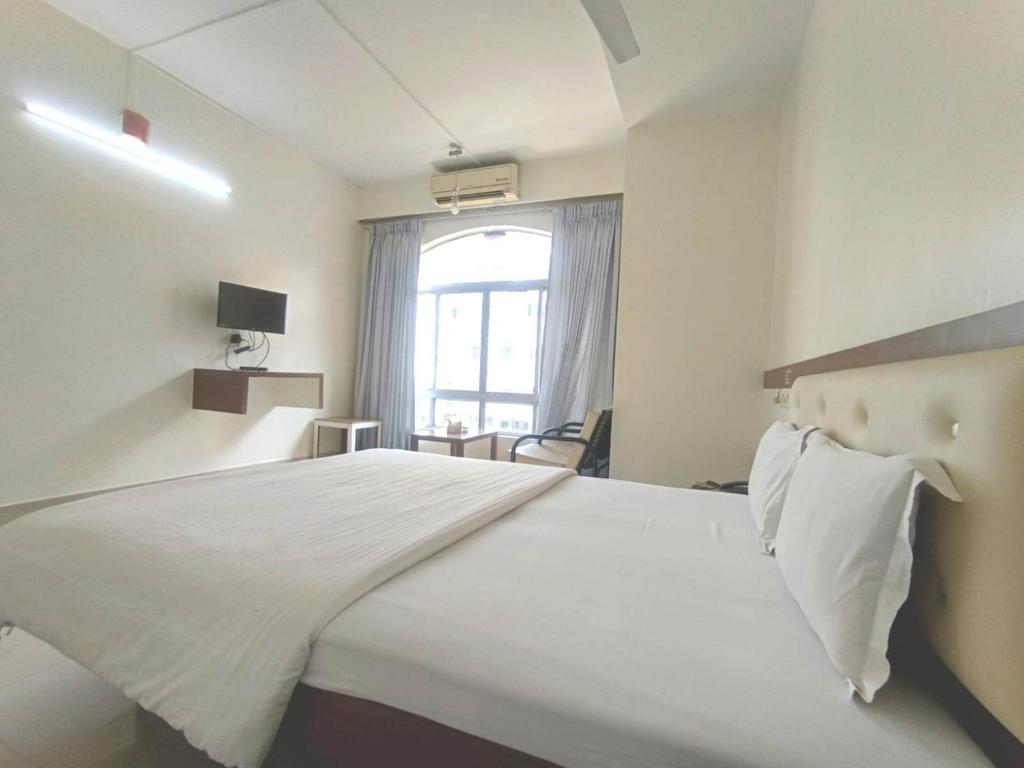 a bedroom with a large white bed with a window at Hotel Rajtara in Satara