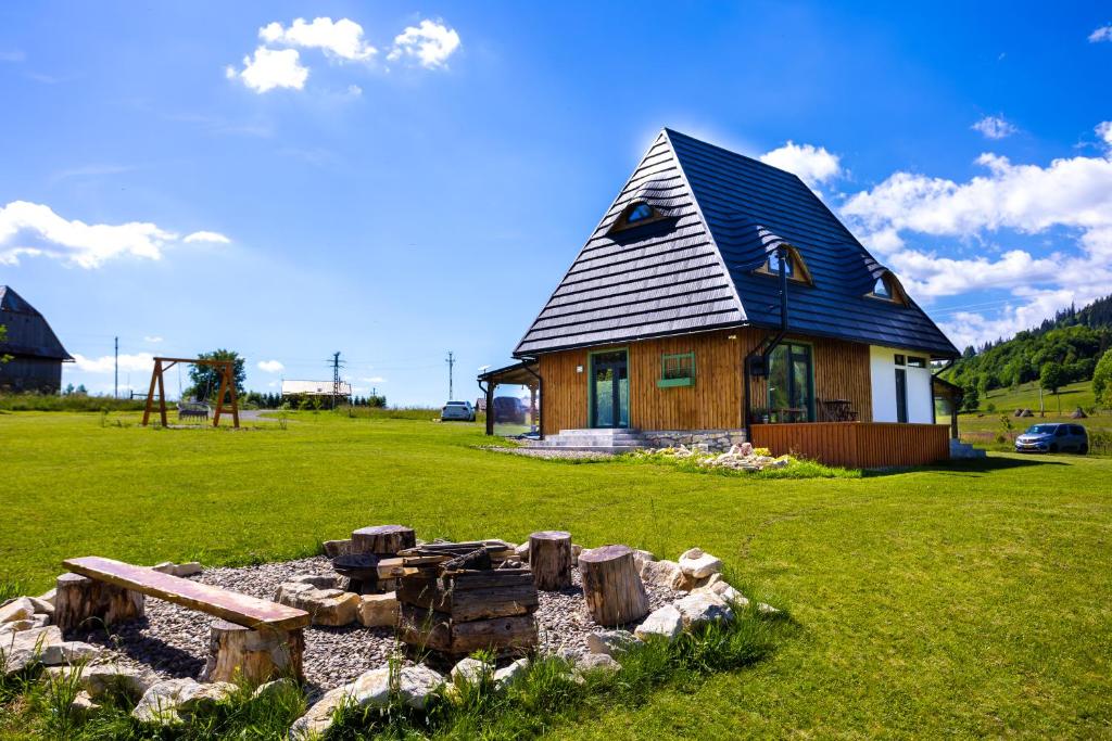 a small house with a gambrel roof on a green field at DejaView Cabin&Camp in Rogojel