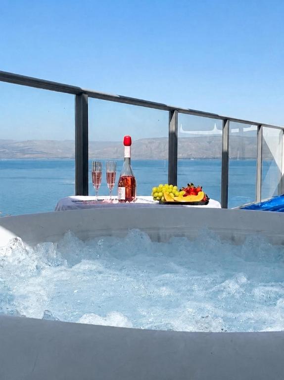 a table with wine glasses and a bottle in a tub at Kinneret Royal Penthouse in Tiberias