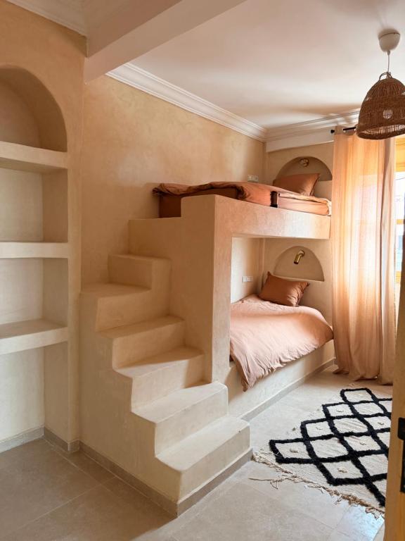 a bedroom with a bunk bed with stairs at Sines Surfmaroc in Tamraght Ouzdar
