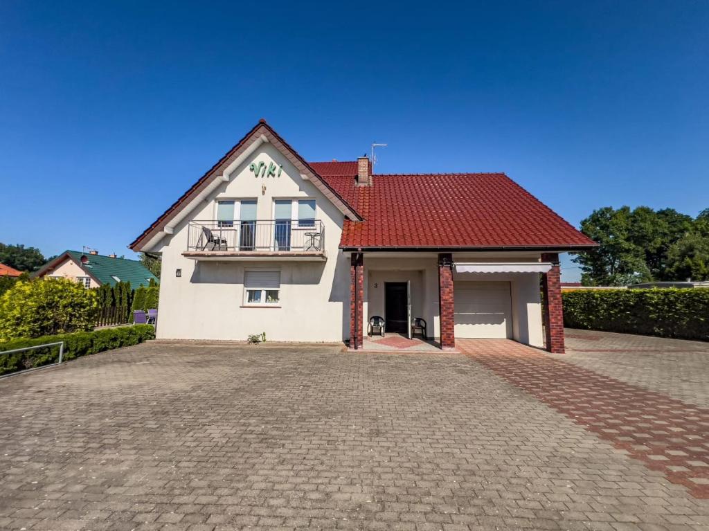 a white house with a red roof and a driveway at Pensjonat Viki in Sarbinowo