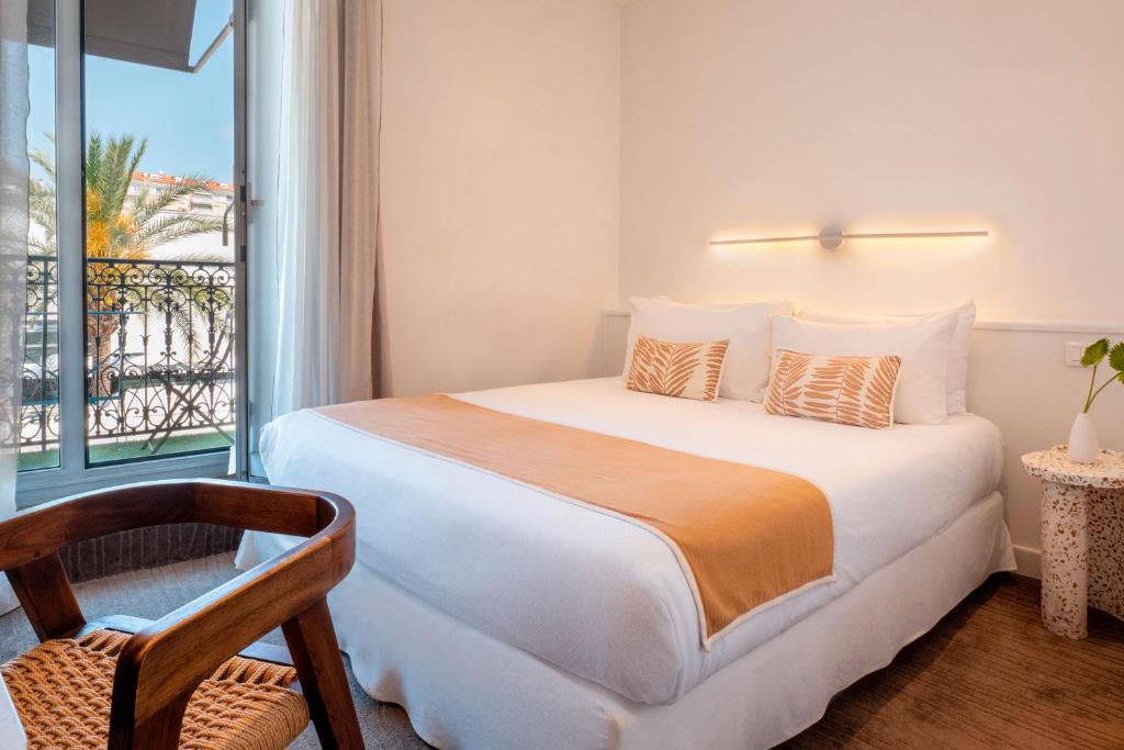 a bedroom with a bed and a window and a chair at Crisol Lumière in Cannes