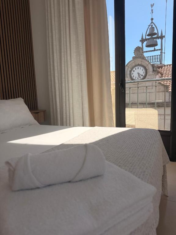 a bedroom with two beds and a clock in the window at Quercus in Pozoblanco