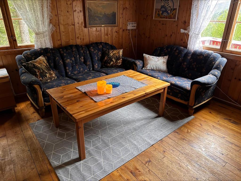 a living room with a couch and a wooden table at Simple and cozy forest cabin in Eidsstryken