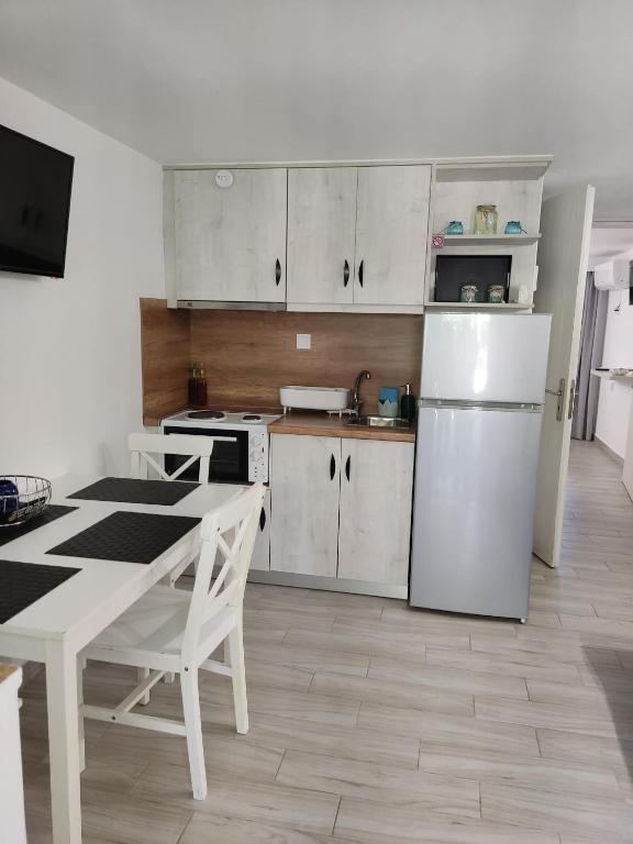 a kitchen with white cabinets and a table and a refrigerator at Calma Kourouta Apartments in Kourouta