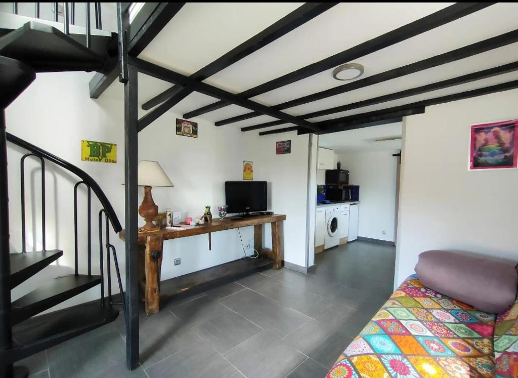 a room with a bed and a desk with a television at Chrisme in Saint-Hilaire-Fontaine