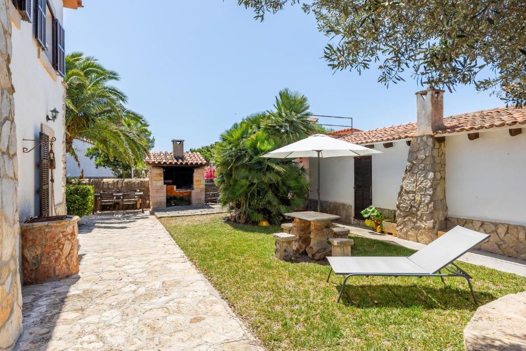 a garden with a chair and an umbrella at Can Jordi in Cala Llombards
