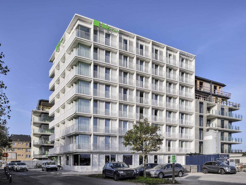 a large white building with cars parked in a parking lot at ibis Styles Bredene in Bredene
