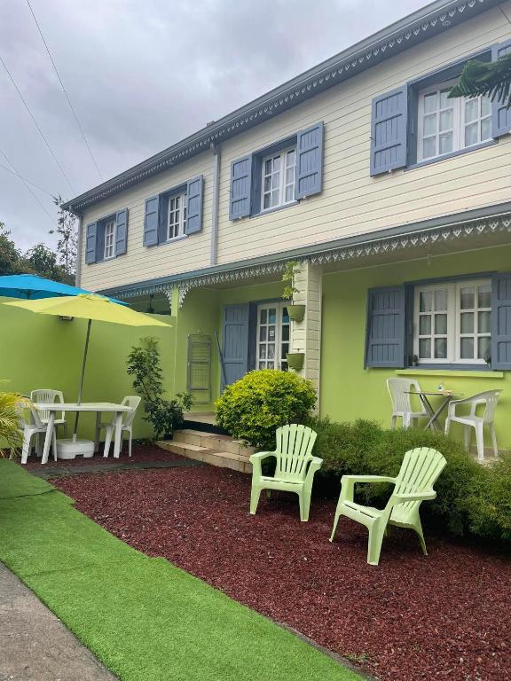 a green house with white chairs and a table at Le camphrier in Salazie
