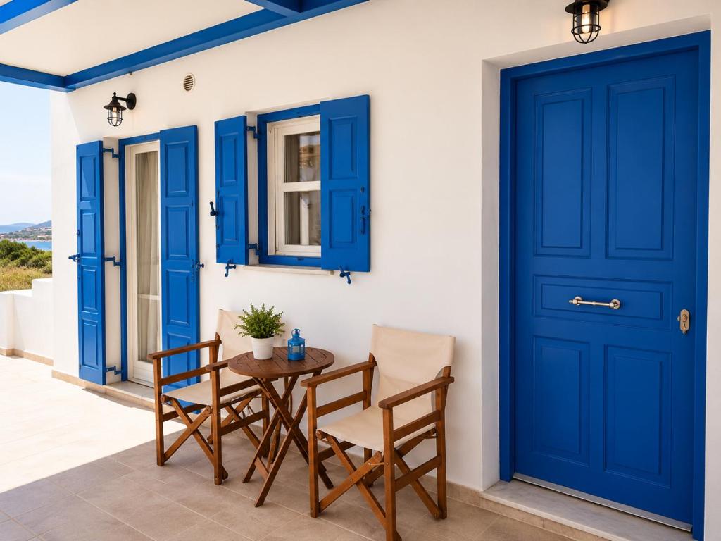 a patio with blue doors and a table and chairs at Crystal Kimolos in Kimolos