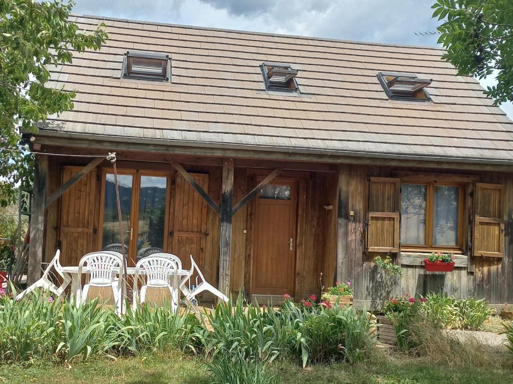 a house with four white chairs in front of it at Isa's Little Cottage in Saint-Bonnet-de-Chirac