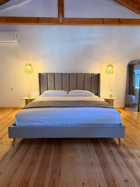 a large bed in a bedroom with wooden floors at Κουρείον Kourion in Agios Vlasios