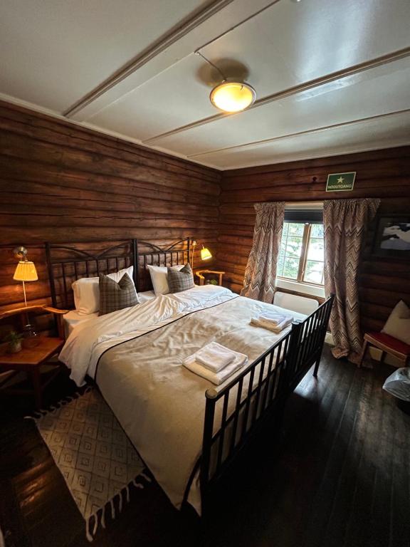 a bedroom with a large bed in a room with wooden walls at Knutehytta in Kongsberg