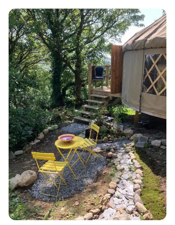a group of yellow chairs and a table in a yard at Fabulous Glamping Yurt in Bantry