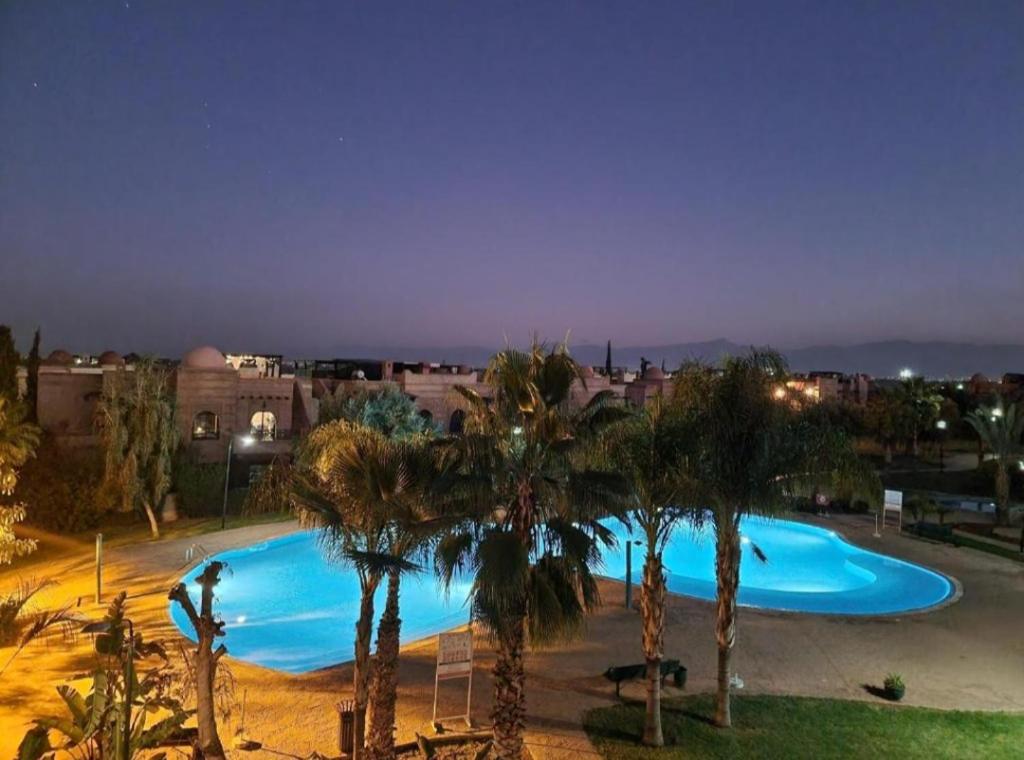 a large swimming pool with palm trees in a city at atlas golf resort in Marrakesh