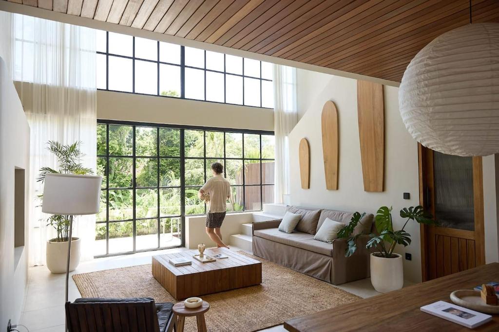 a man standing in a living room looking out the window at The Young Villas Tropical Villas in Seseh in Canggu