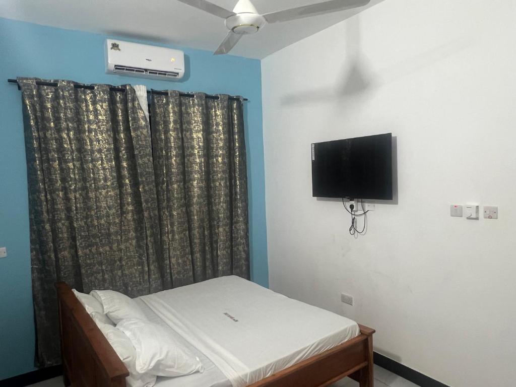 a bedroom with a bed and a tv on the wall at New Ndani Lodge in Tanga