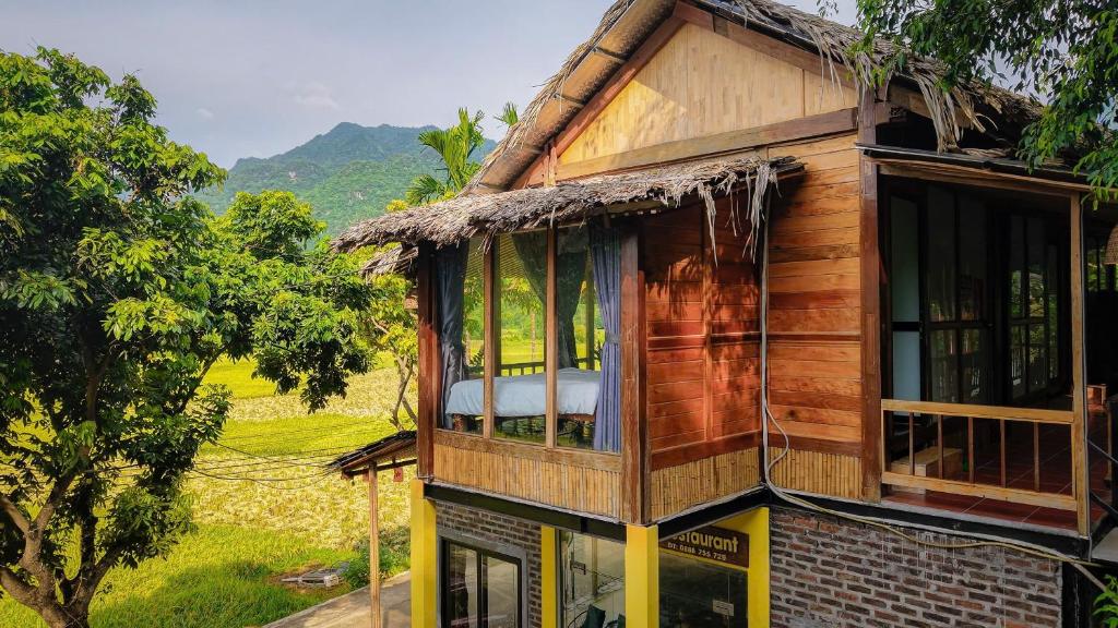 a wooden house with a window and a field at Mai Chau Mountain Delight in Mai Châu