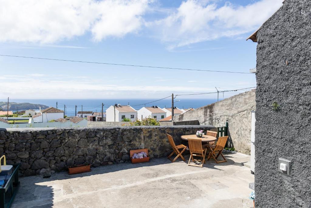 eine Terrasse mit Tisch und Stühlen und einer Steinmauer in der Unterkunft Casa do Armando in Achadinha