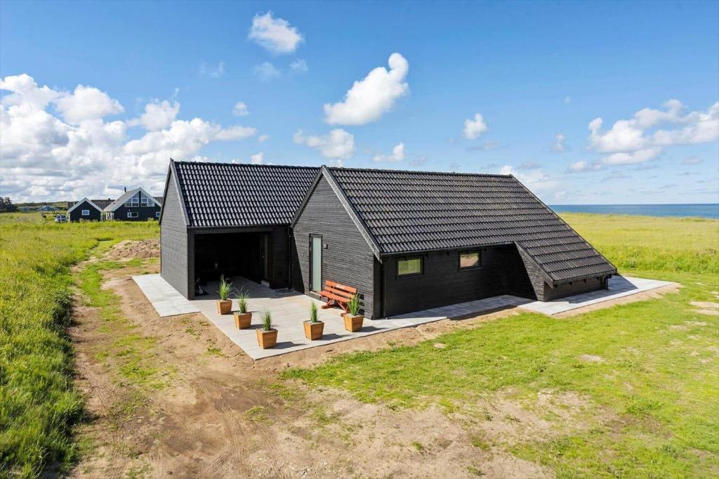 a black house with potted plants in a field at LN2067-Hjorring-Gabet-7 in Lønstrup