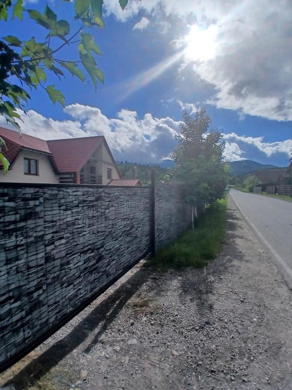 a stone fence next to a road next to a house at Садиба Сонячний дім in Pilipets