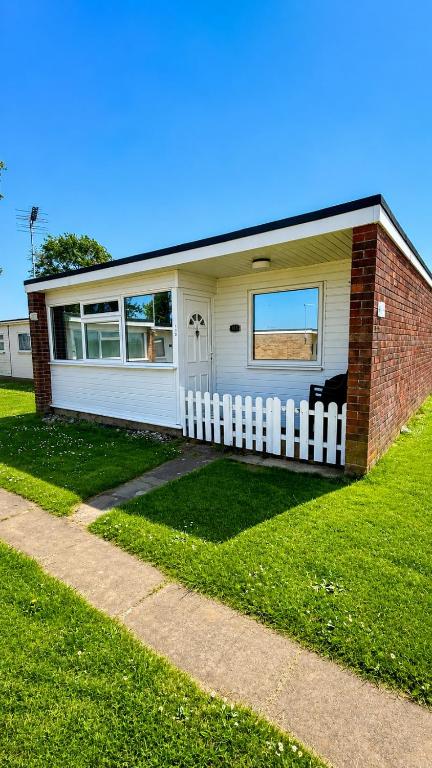 a house with a white fence in the grass at The Three bs in Scratby